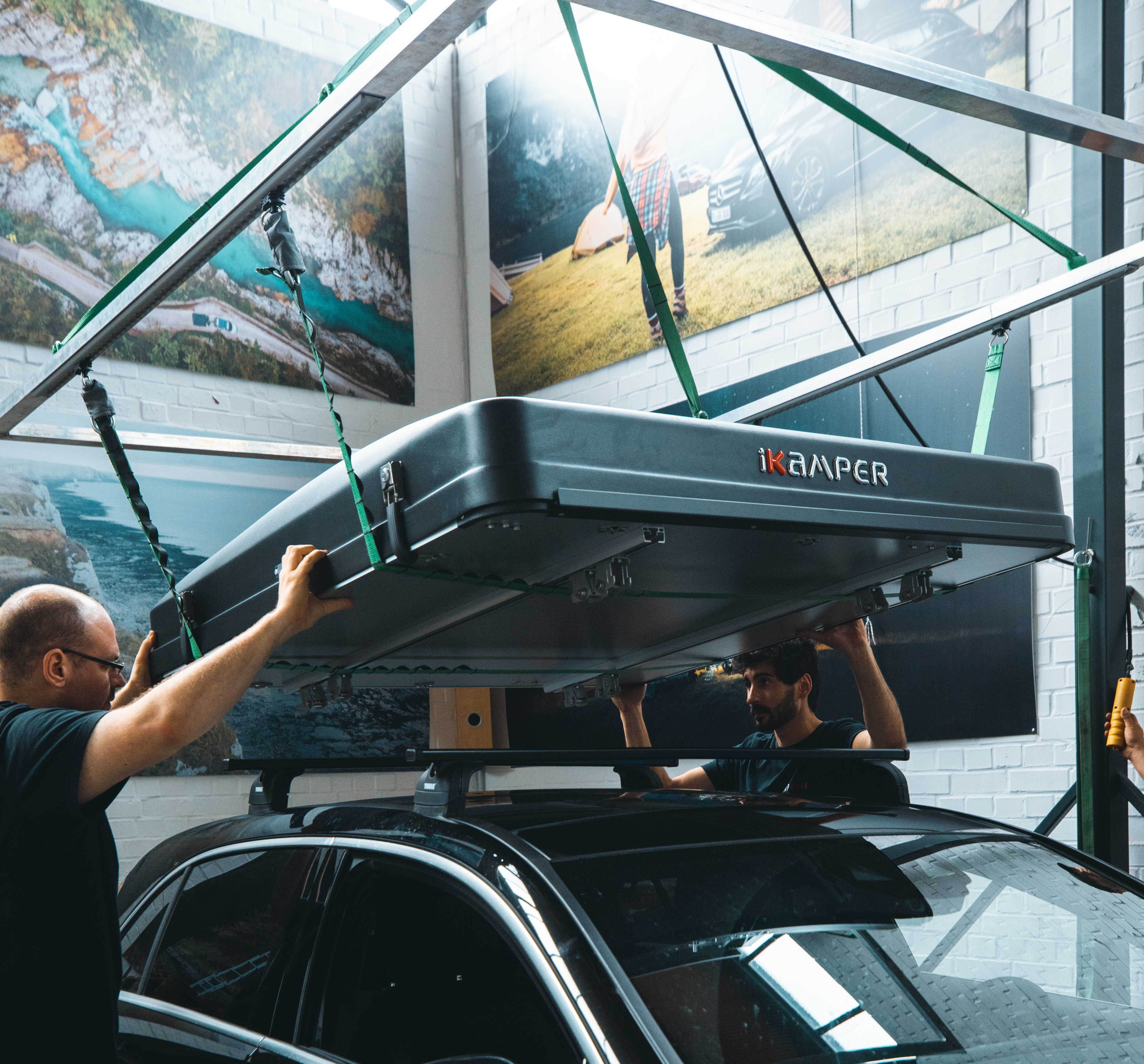Two people are mounting a roof tent on a car