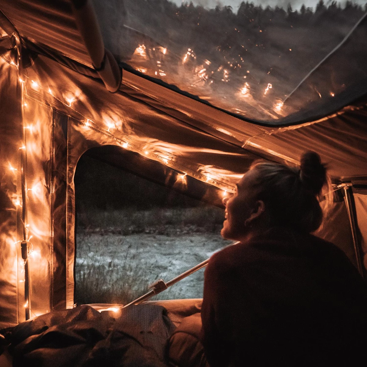 Cozy camping atmosphere in the roof tent with warm fairy lights.