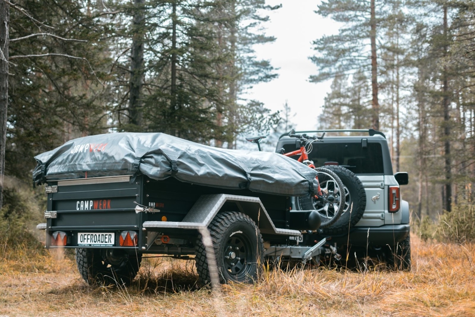 A car with a tent trailer uncoupled on a forest path