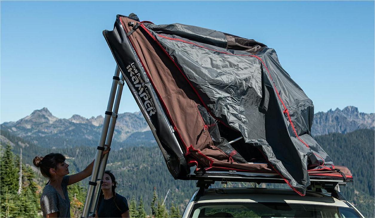 Two women dismantle their roof tent